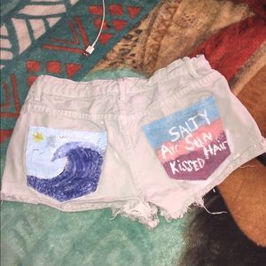 White jean shorts with acrylic paint on pockets.